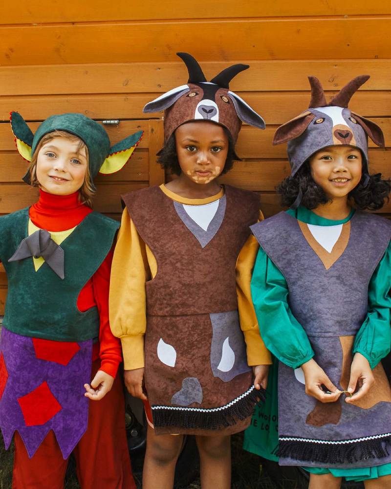 3 children standing in a row, two are wearing the billy goat hat and tabard and the third is wearing the troll hat and tabard.