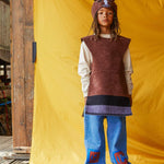 Child wearing the brown horse hat and tabard, standing in front of a bright yellow fabric background.
