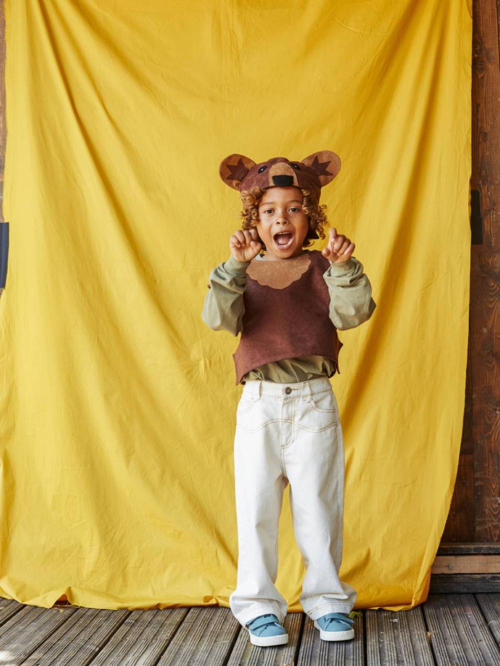 Boy wearing the brown bear costume, pretending to growl at the camera.