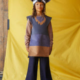 Child wearing the grey wolf hat and tabard, standing against a yellow fabric background.