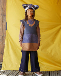 Child wearing the grey wolf hat and tabard, standing against a yellow fabric background.