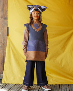 Child wearing the grey wolf hat and tabard, standing against a yellow fabric background.