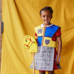 Girl carrying a yellow hobby horse and wearing the fairytale knight tabard and cuffs