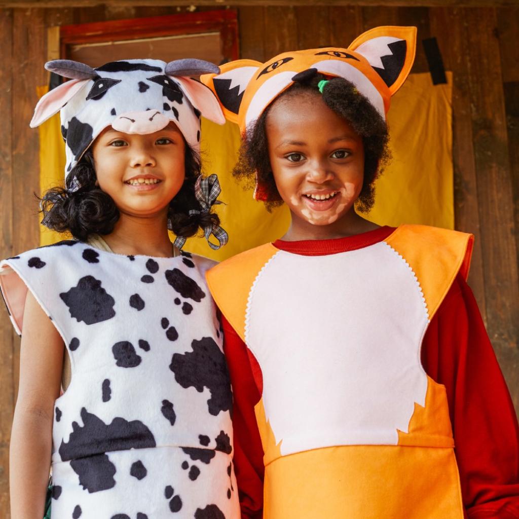 Two children in animal costumes standing next to each other outdoors.