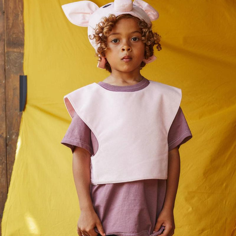Child wearing the pink pig hat and tabard.
