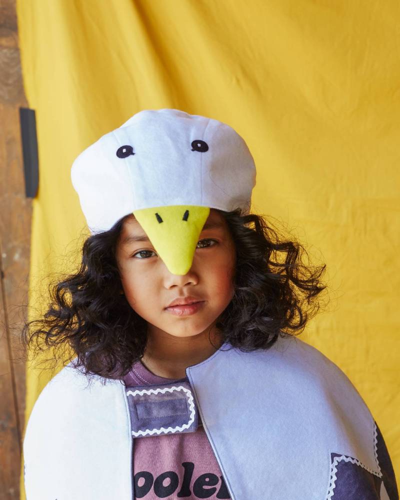 Child wearing the white duck hat and white feathered bird cape.