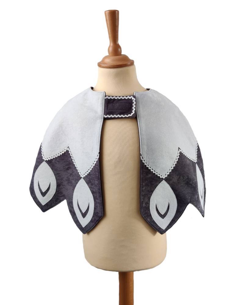 Front view of white feathered bird cape on a stand against white background.