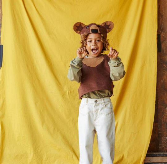 Child wearing a bear costume with a yellow curtain background
